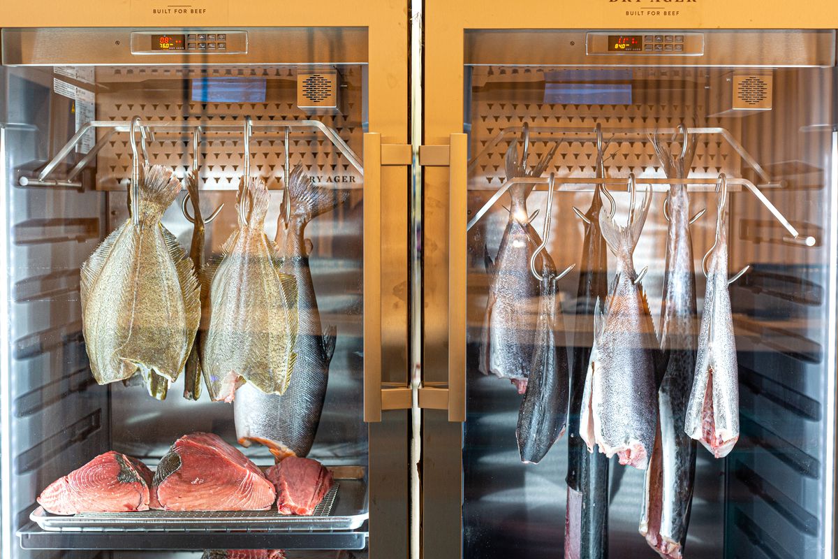 Headless fish dry-aging and hanging down in a case at Sushi by Hidden.