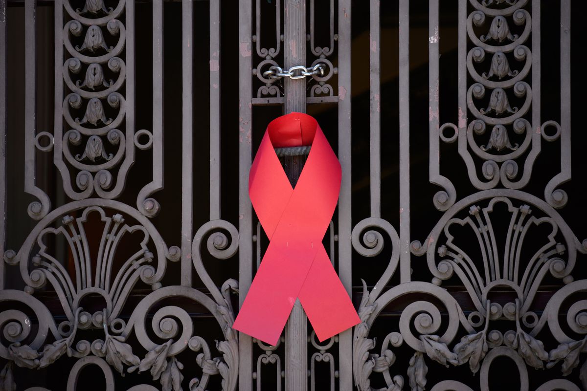 A red ribbon for HIV awareness hangs at a gate.