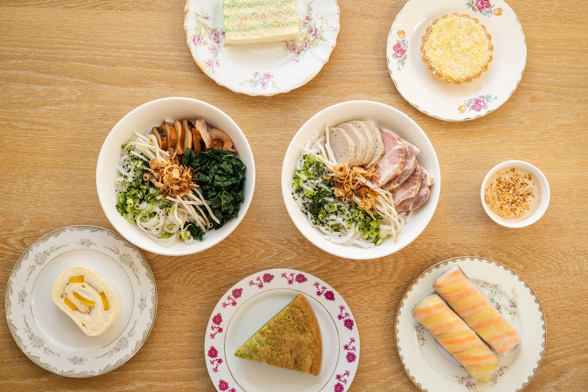 A table at Berlu is covered in bowls of noodle soup, slices of cake, and other pastries