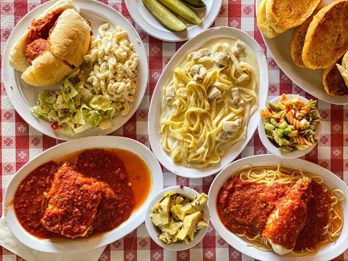 A red checkered table with Italian dishes like lasagna and chicken parm.