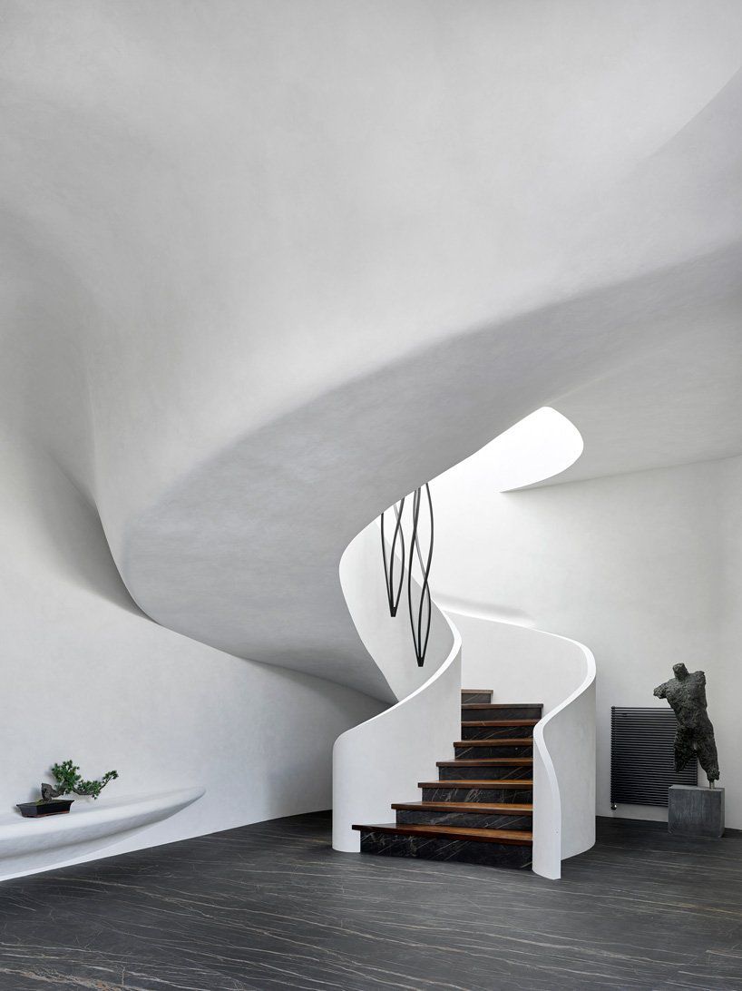 Curving white staircase and brown floors. 