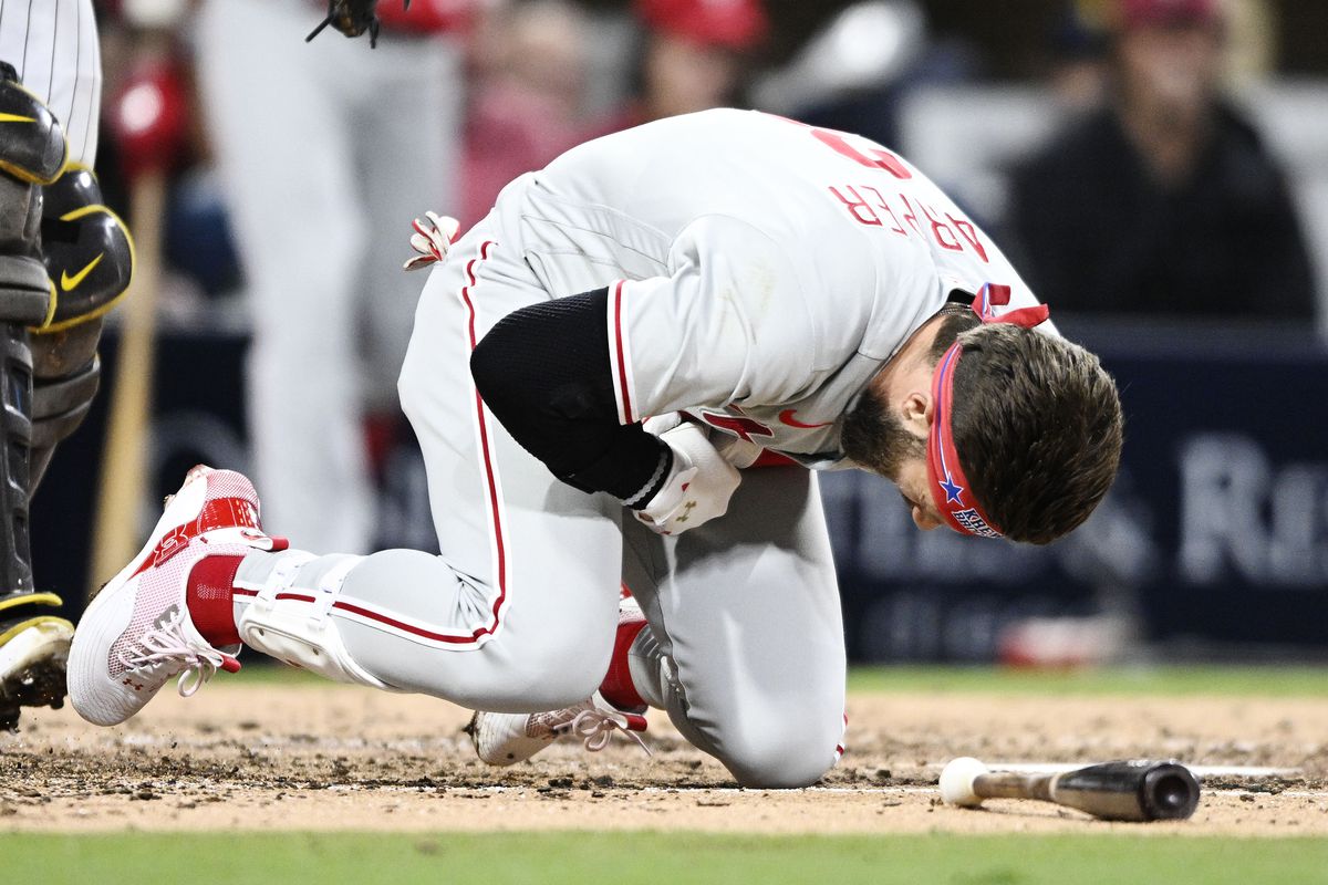 Bryce Harper #3 of the Philadelphia Phillies falls after being hit with a pitch during the fourth inning of a baseball game against the San Diego Padres June 25, 2022 at Petco Park in San Diego, California.