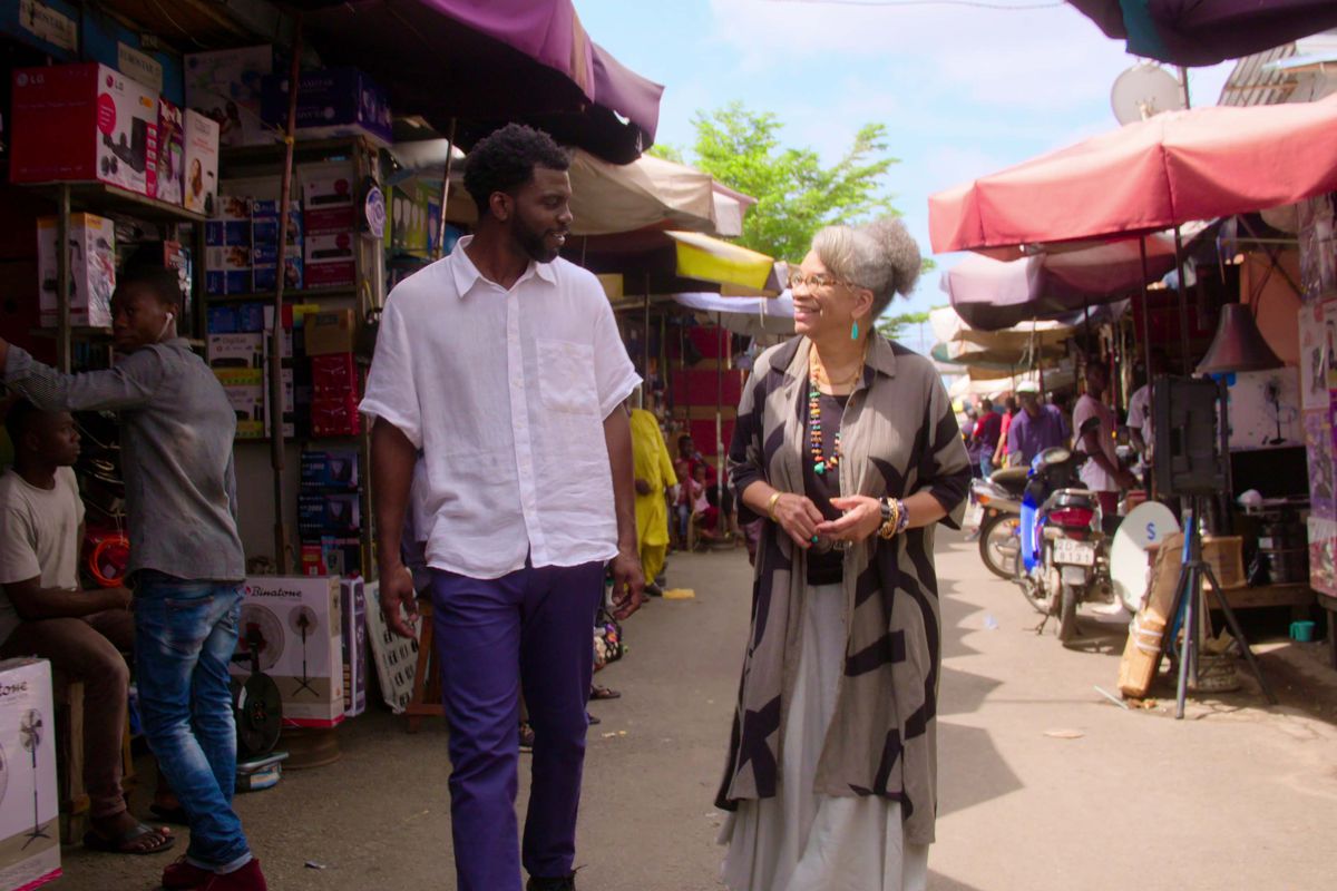 A man and woman walk in an outdoor market