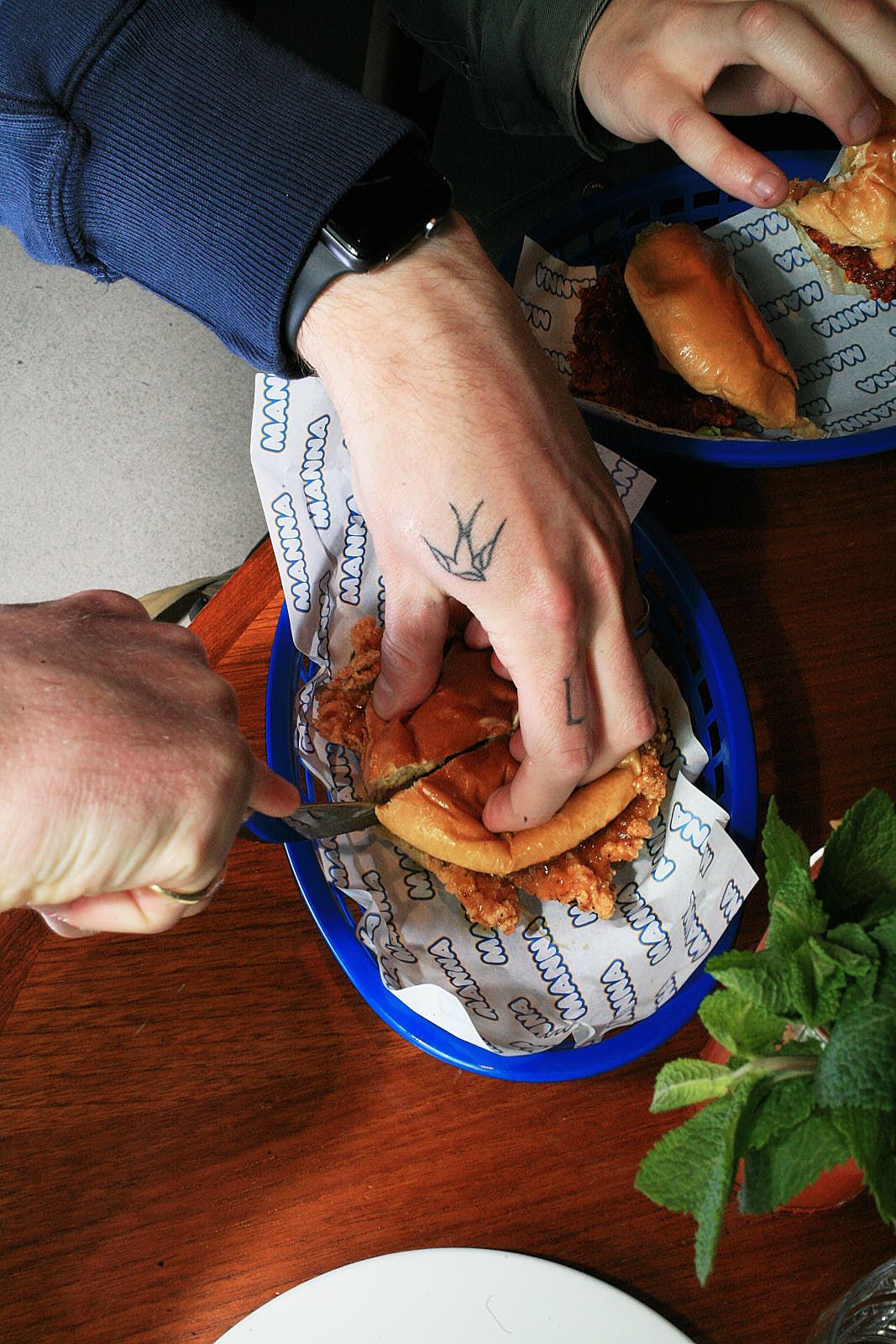Cutting in to a jalapeño popper chicken burger, again in a blue diner-style basket