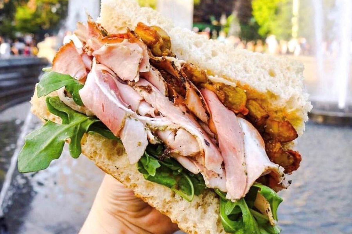 A sandwich from Italy protrudes with sliced meat and focaccia.