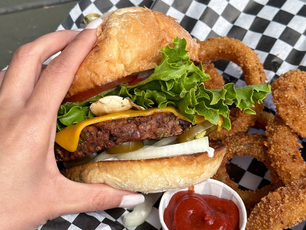 A photo of Cozo Grill’s black bean burger with a side of onion rings and ketchup.