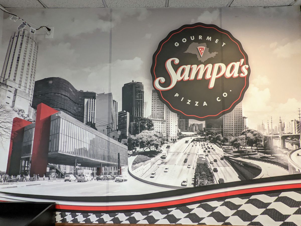 Wall mural of black and white photo and signage of pizza restaurant.
