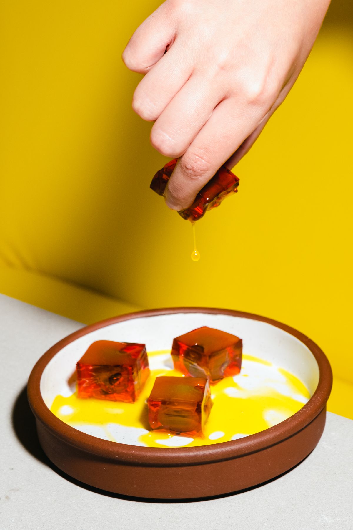 A hand holding a Negroni jelly olive.