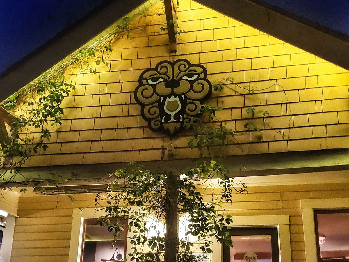 The exterior of Little Beast is shown at night, illuminated yellow with lighting under the eaves.