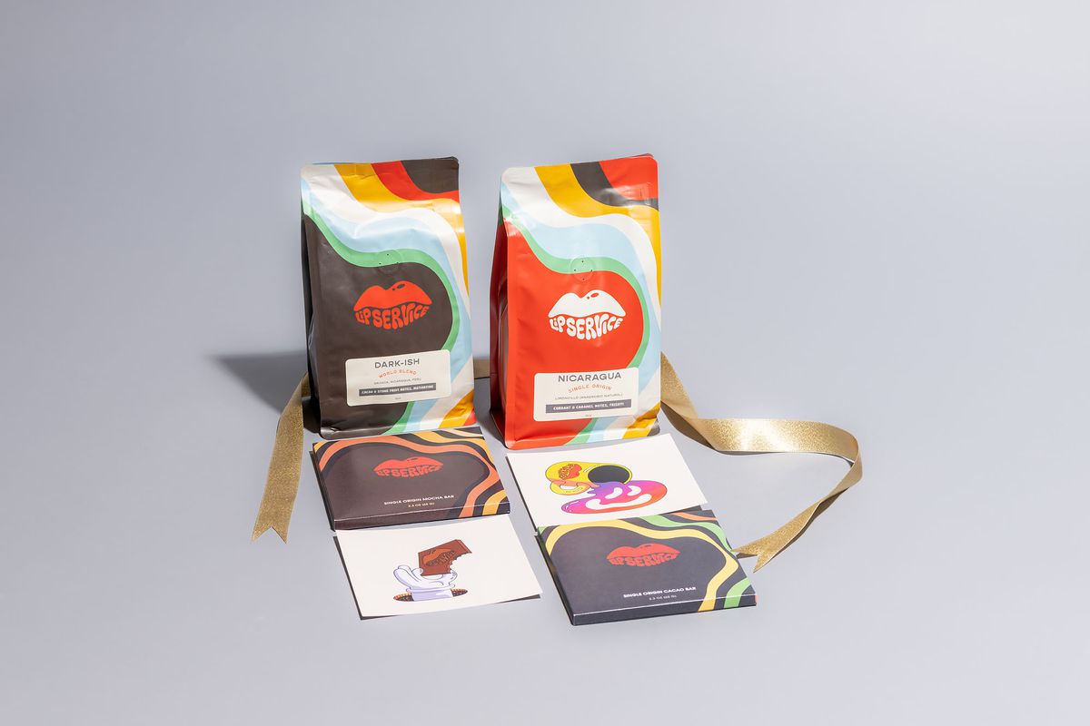 Two bags of coffee and two square chocolate bars from Lip Service, all with colorful labels featuring a pair of lips, wrapped in a gold ribbon.
