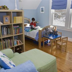 Parker Hirsch reads in his redecorated room. His new bed is high enough for storage underneath, and a bookcase tames his book collection.