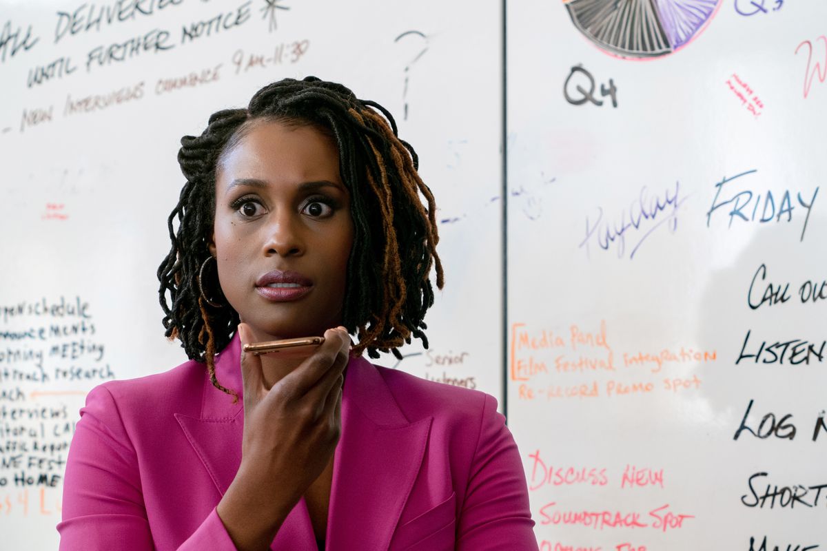 Issa Rae looks weirded out while talking into a phone in front of a whiteboard covered in colorful notes