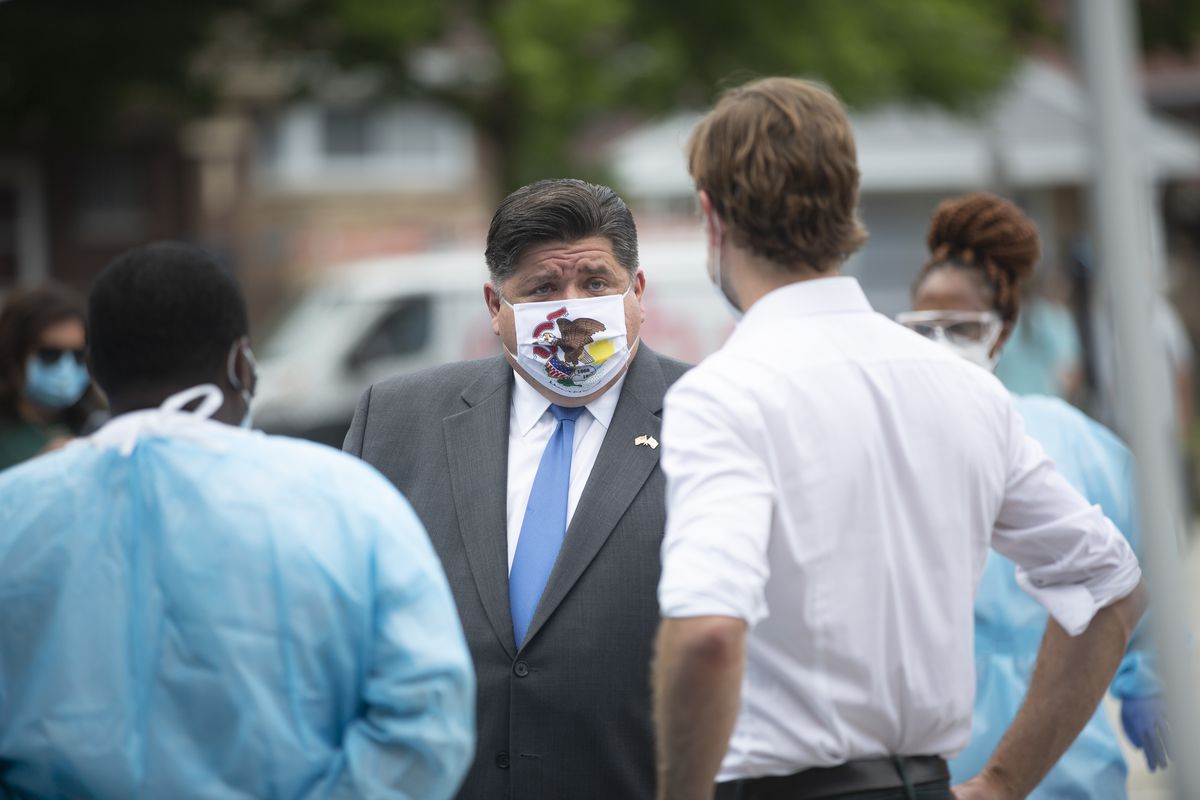 Gov. J.B. Pritzker speaks to medical personnel during a visit to a mobile COVID-19 testing station at Edward Coles School in the South Chicago neighborhood in July.