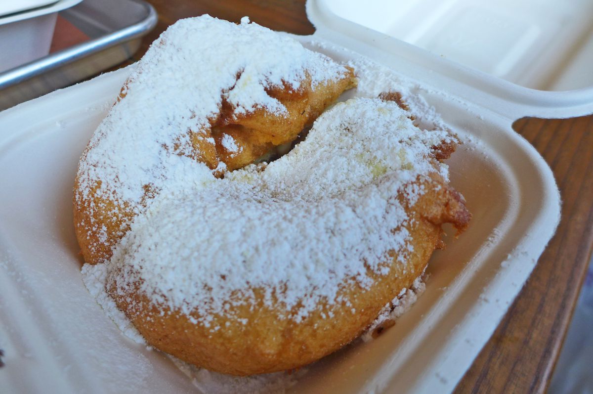 Inside a white flip open container a double mass covered with powdered sugar.