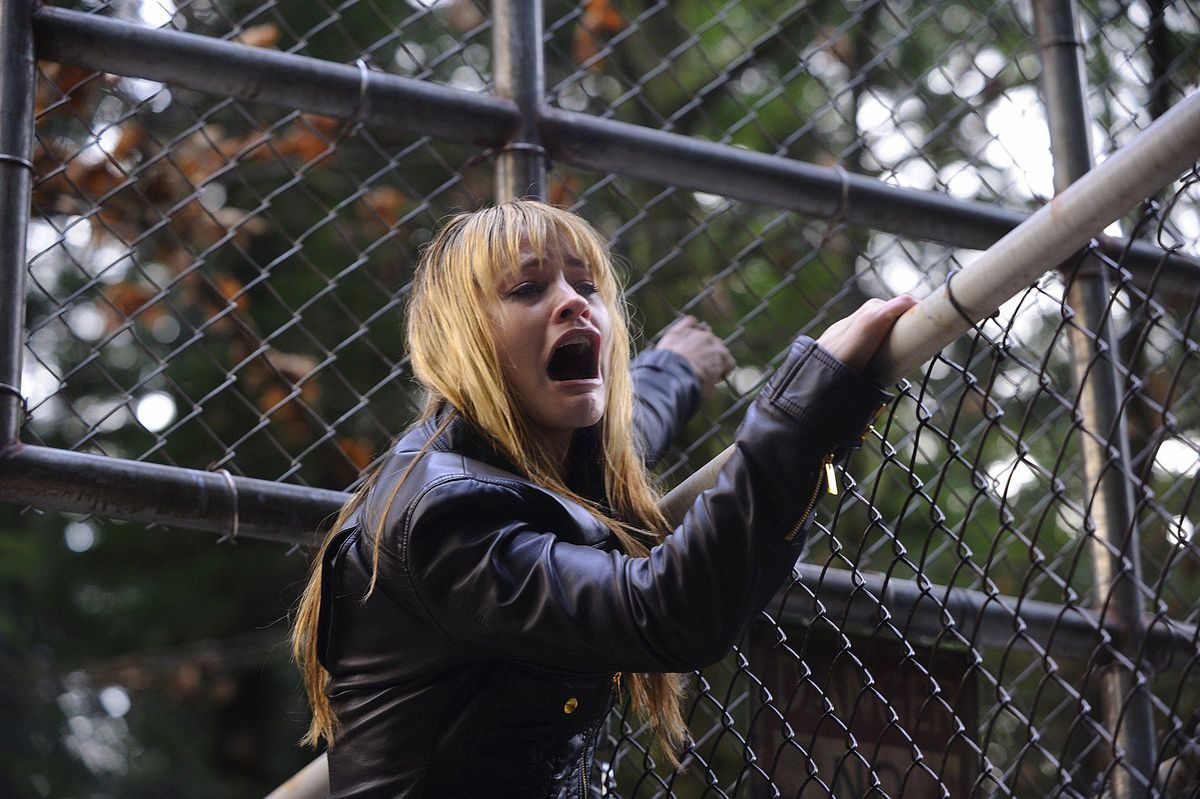 A blonde woman (Cameron Richardson) screams in terror while climbing a fence in Harper’s Island.