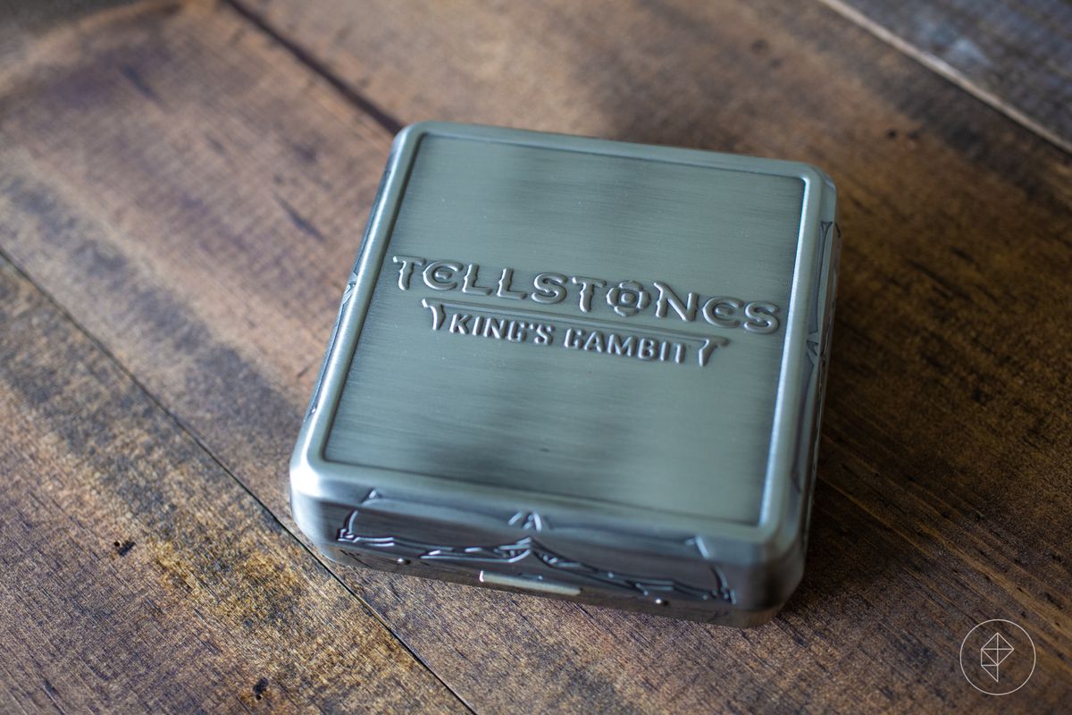 A brushed silver box with a button sits on a wooden table.