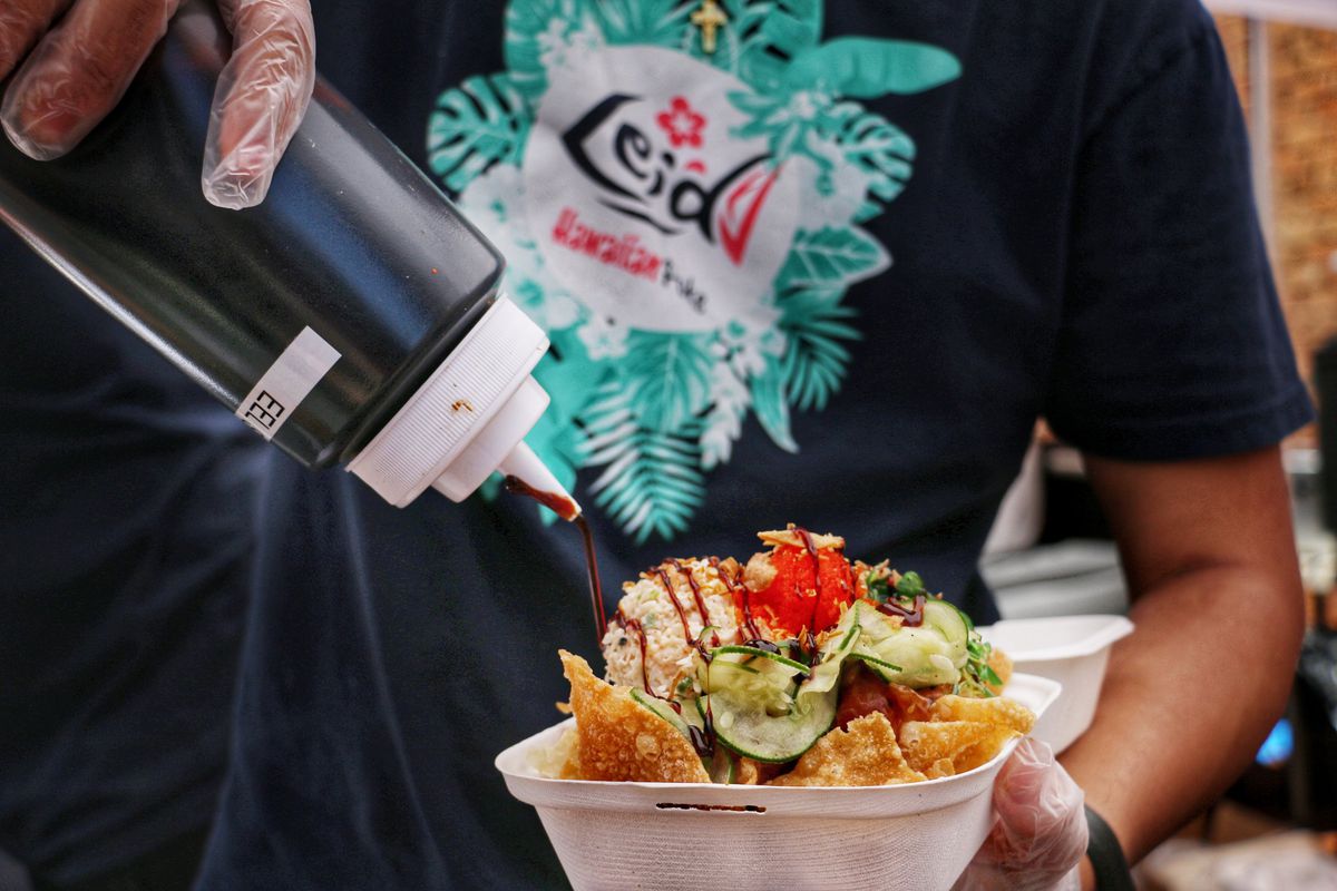 A Lei’d chef dresses a tray of poke nachos with eel sauce