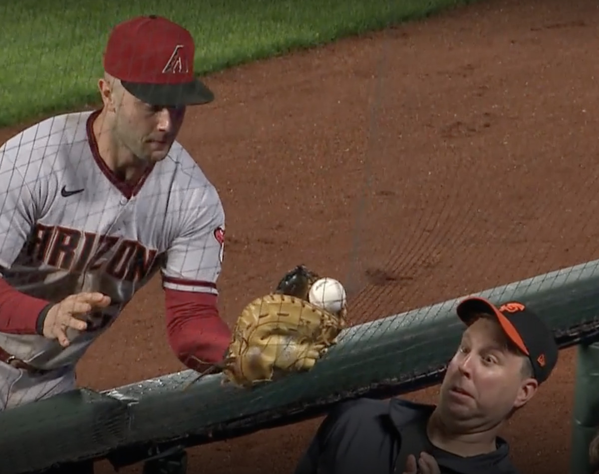 A fan makes a funny face as a foul ball hits the screen in front of him and a Diamondbacks outfielder tries to catch it