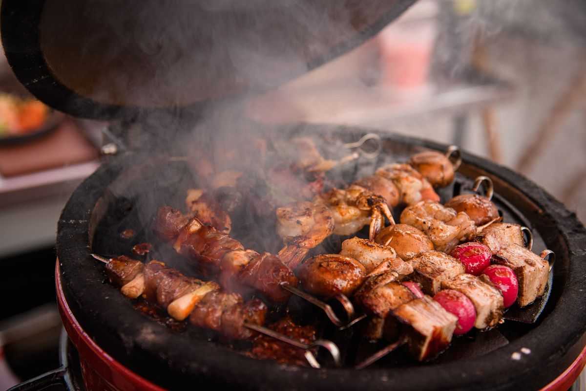 Skewers of meat cooking on a grill.