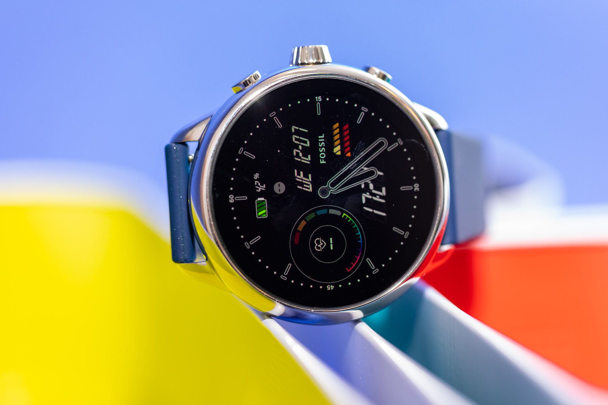 Close up of the Fossil Gen 6 Wellness Edition’s watch face while it sits atop colorful bins