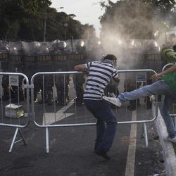 A protester kicks another one as he tried to prevent him from breaking a police barrier during a protest outside Minerao stadium where a Confederations Cup soccer match takes place between Japan and Mexico in Belo Horizonte, Brazil, Saturday, June 22, 2013. Demonstrators once again took to the streets of Brazil on Saturday, continuing a wave of protests that have shaken the nation and pushed the government to promise a crackdown on corruption and greater spending on social services. 