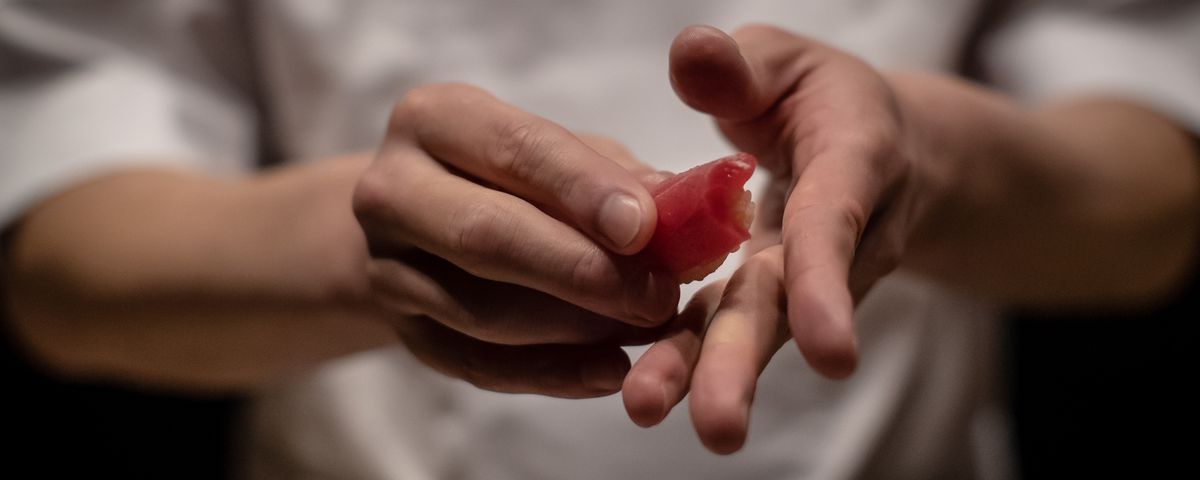 Chef Shigeyuki Tsunoda, in a close-up shot showing only his hands, prepares crimson lean tuna nigiri sushi
