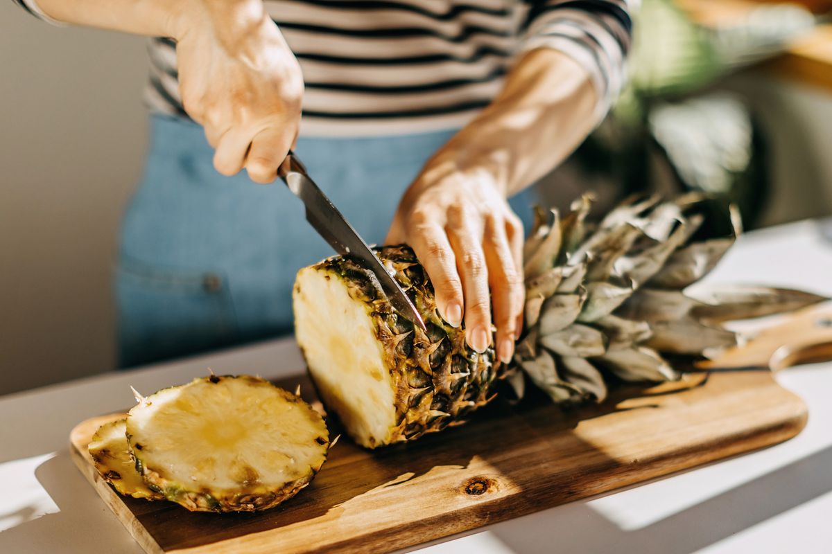 Woman cutting pineapple on countertop