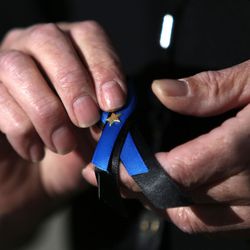 A West Valley animal officer puts on a ribbon to honor West Valley police officer Cody Brotherson at his funeral at the Maverik Center in West Valley City on Monday, Nov. 14, 2016.