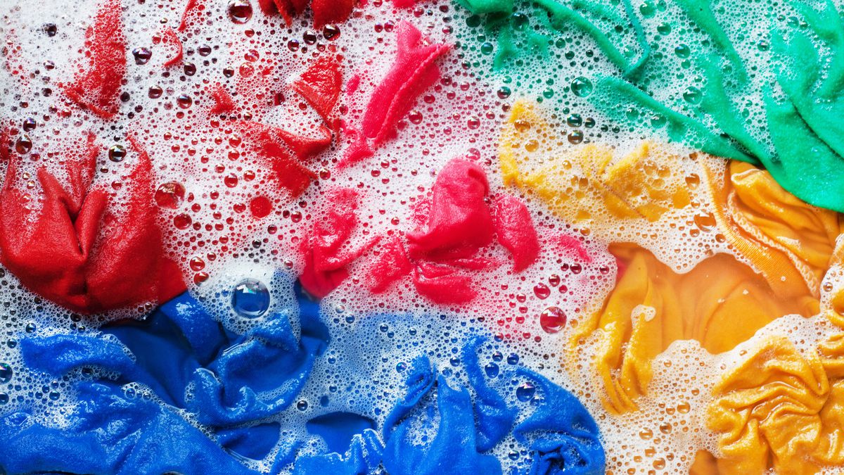 red, blue, yellow, and green items of clothing submerged in water and suds