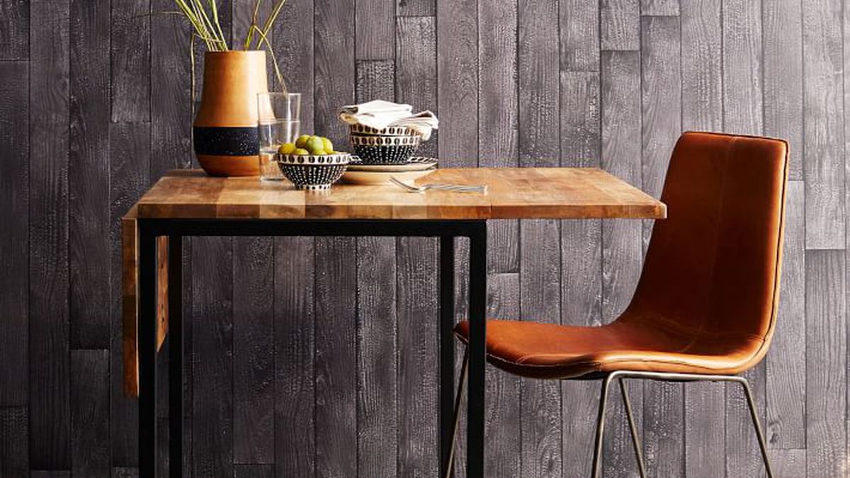 A wood and metal table sits next to a leather chair.