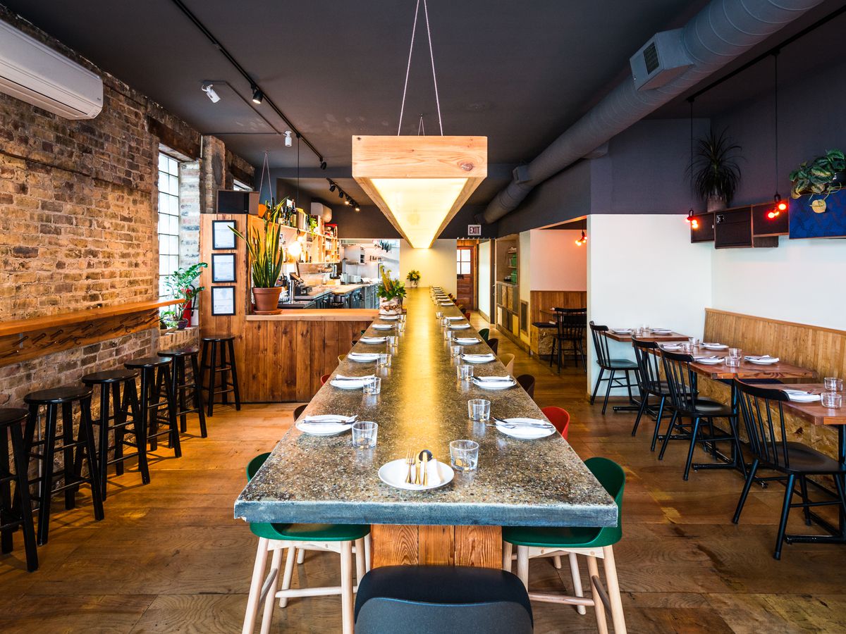 The interior of Parachute restaurant in Chicago, with a long communal table in the middle and seating to each side, one of the city’s best restaurants for a first date. 