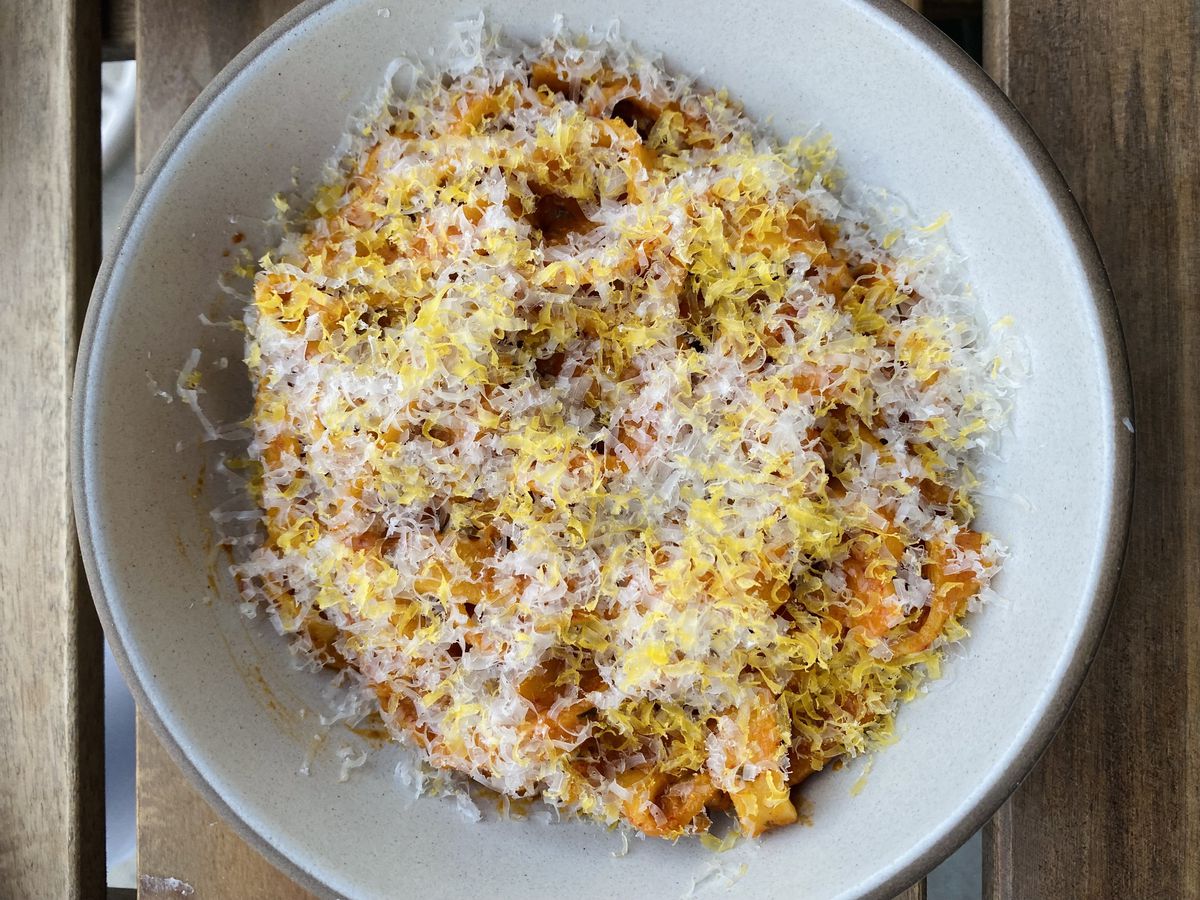 A bowl of red-sauced tagliatelle topped with parmesan and grated egg yolk.