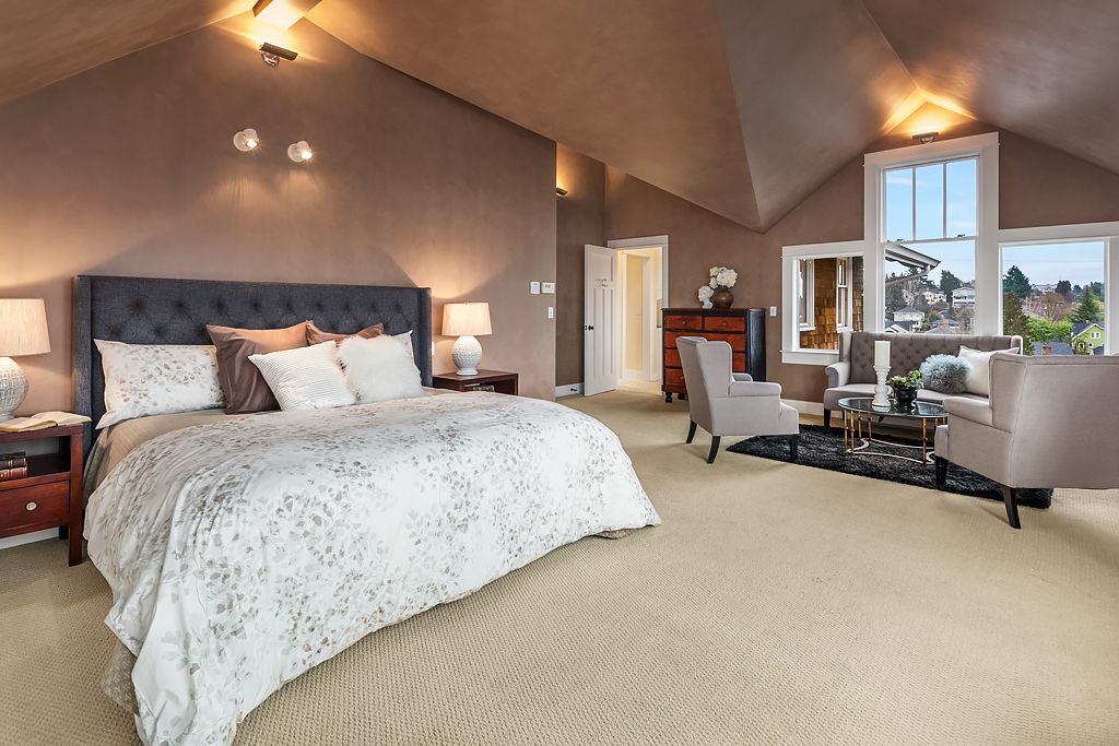 A large bedroom with vaulted ceilings and a sitting area off to the right