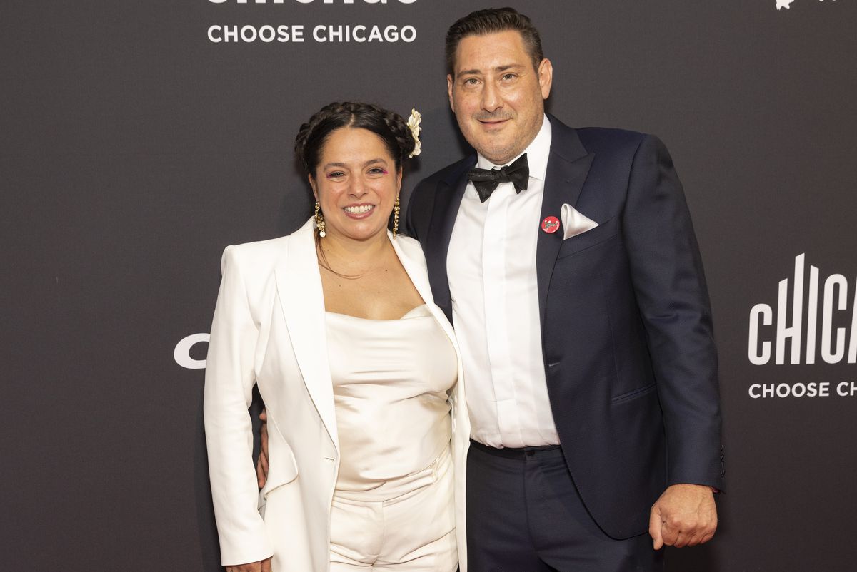 A woman and a man pose and smile on a red carpet.