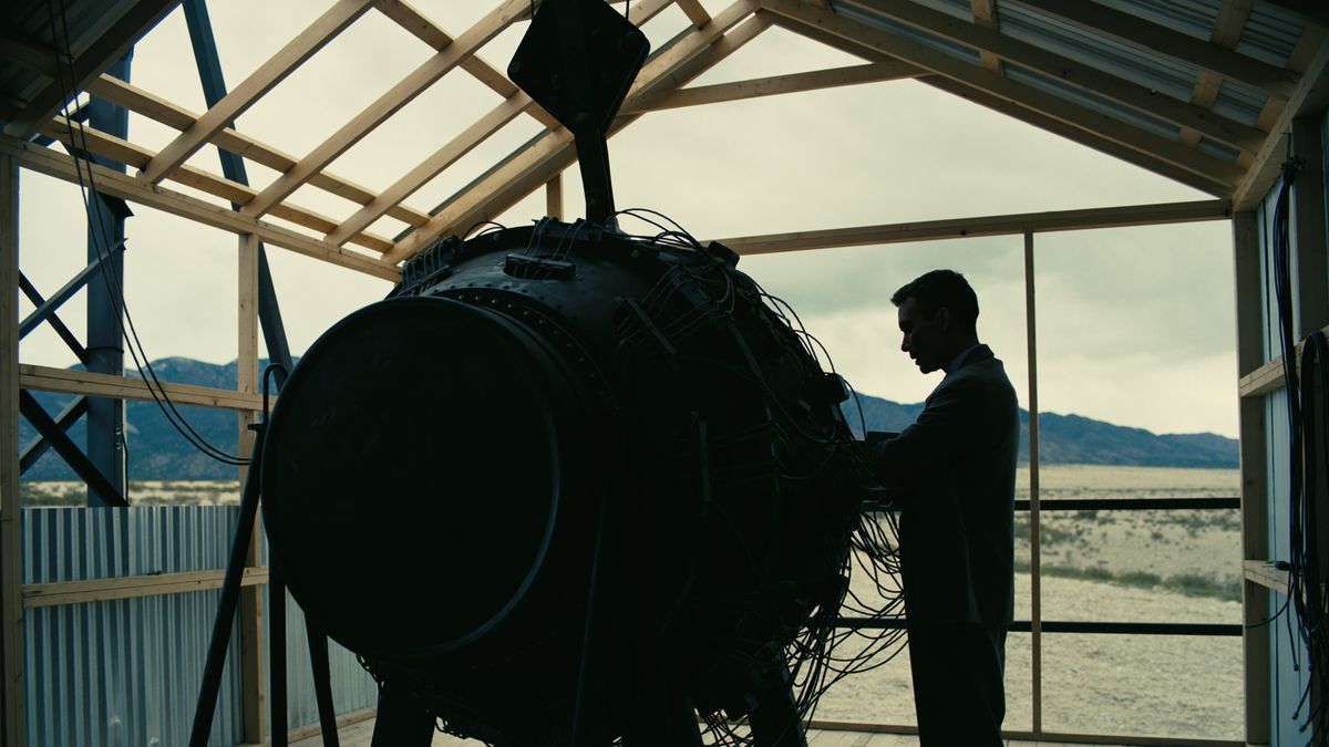 J. Robert Oppenheimer stands in silhouette on a tower with his test atomic bomb over the New Mexico desert in a scene from the film Oppenheimer.
