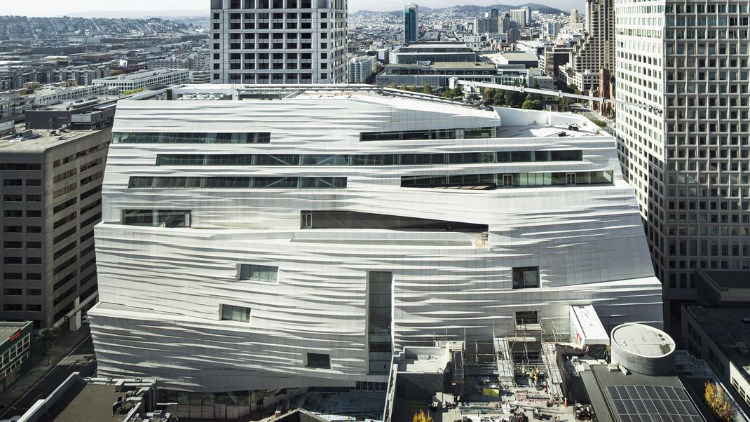 The exterior of the San Francisco Museum of Modern Art. The facade is white and contoured giving it a wavy appearance.