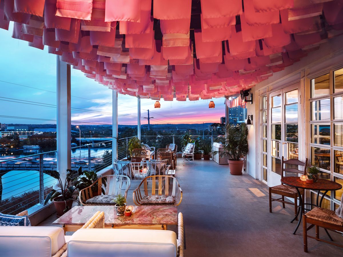 A rooftop bar at sunset with a patio and hanging lanterns.