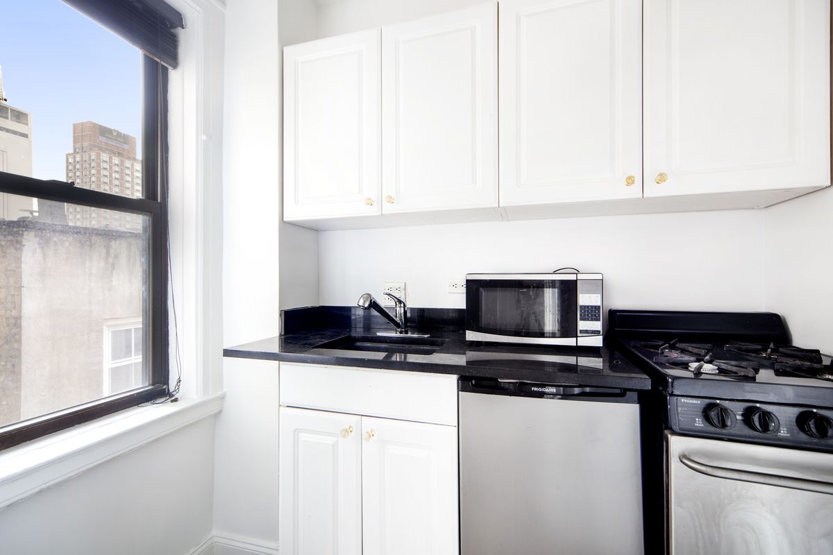 A kitchen with white cabinetry and a window.