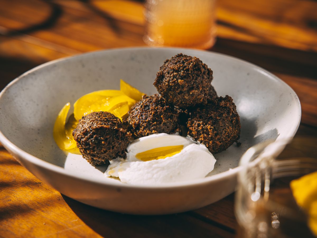 A shallow bowl of falafel bals and a white cream dollop.