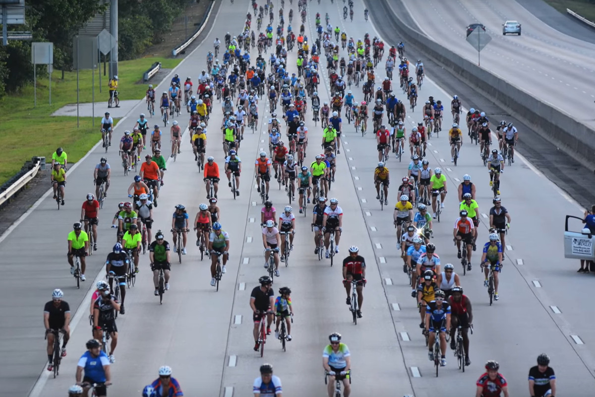 A swarm of cyclists pedal down the interstate.