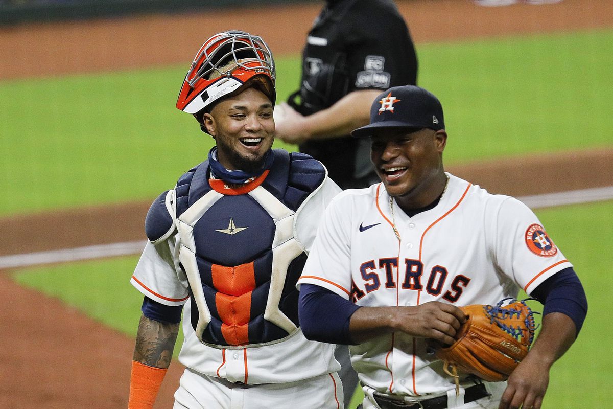 Framber Valdez #59 of the Houston Astros and Martin Maldonado #15 laugh after a ground ball was back up the middle and almost hit Valdez in the sixth inning against the Texas Rangers at Minute Maid Park on September 17, 2020 in Houston, Texas.