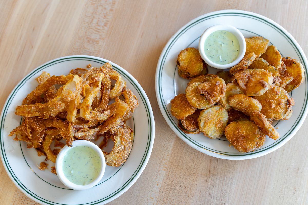 Two round plates of fried food sit side by side.