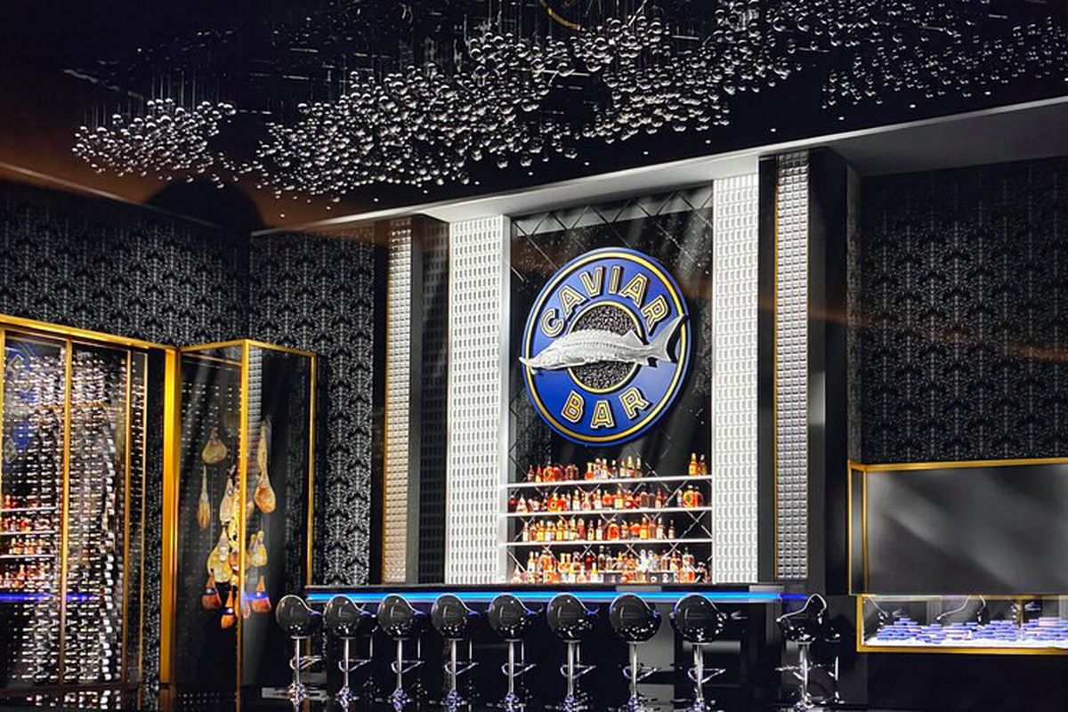 A dark bar with a sturgeon logo behind it and stools with blue seats,