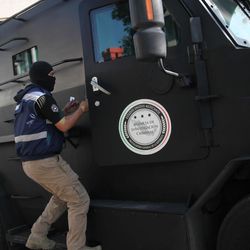 A masked federal police officer stands on an armored vehicle arriving as part of beefed up security outside the SEIDO, the organized-crime division of Mexico's Attorney General Office where high profile detainees are sometimes shown to the press in Mexico City, Friday, Feb. 27, 2015. Leader of the Knights Templar cartel Servando "La Tuta" Gomez," one of Mexico's most-wanted drug lords, was captured early Friday by federal police in the capital city of Morelia, according to a Mexican official. It could not be confirmed if Gomez was inside the building. 