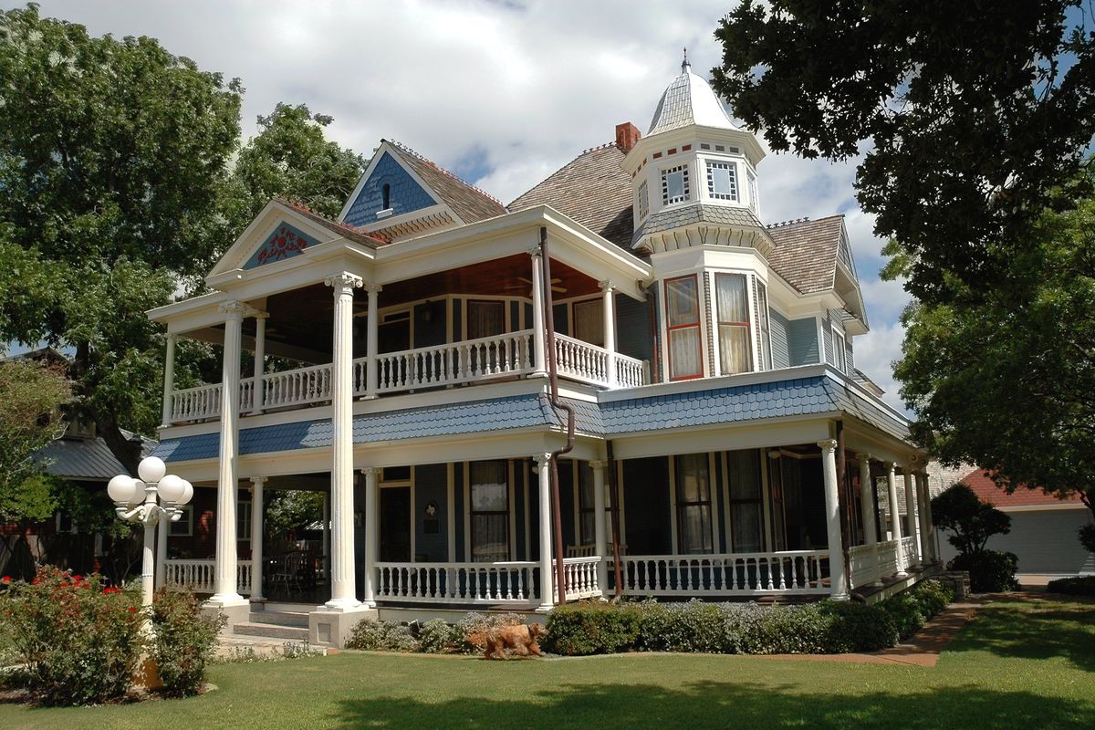 A victorian texan two-story blue home, with both story wrap around porches 