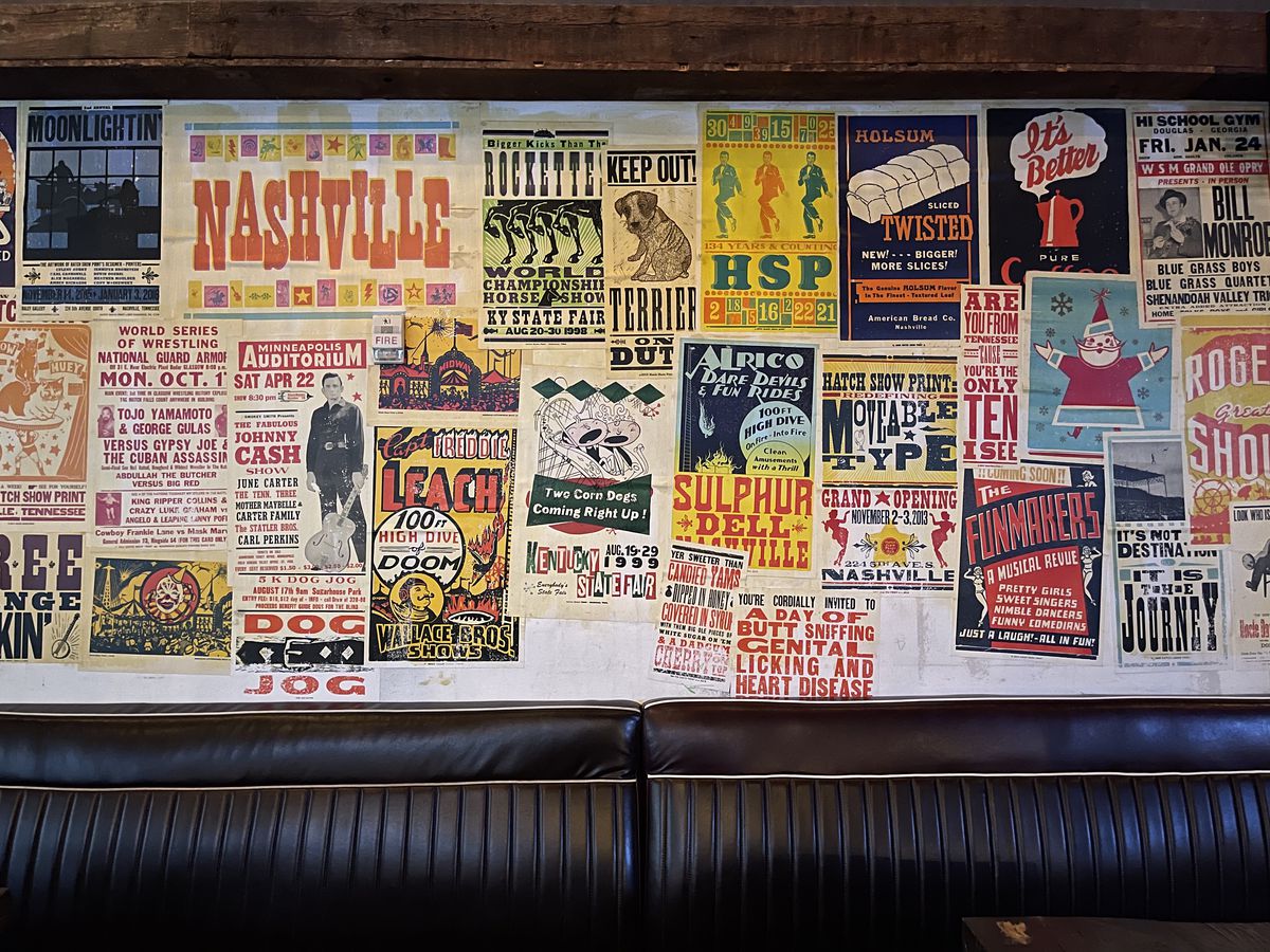 Posters for various Nashville music events above a black banquette.