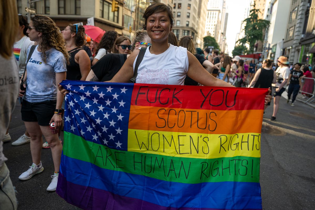 An abortion rights supporter holds a rainbow-colored American flag with text slamming the Supreme Court’s Roe v. Wade reversal during a pride march in New York on June 25.