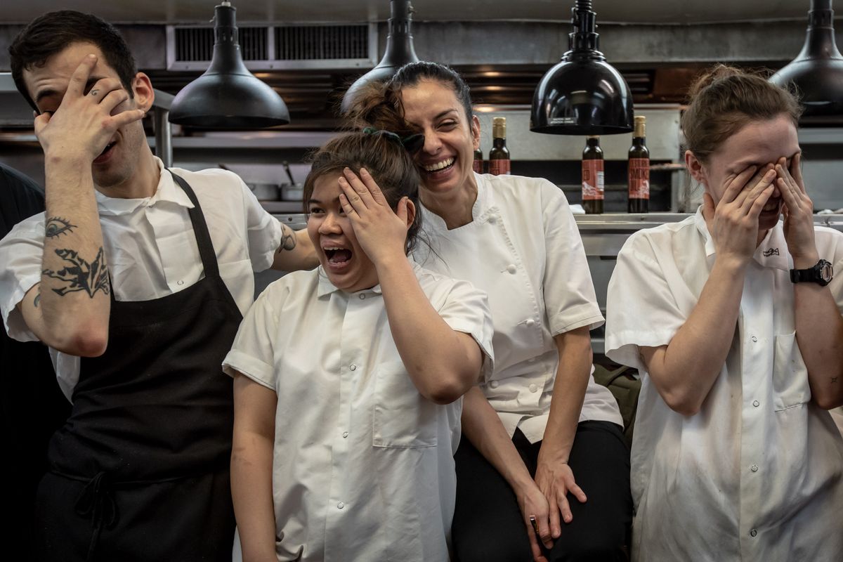 Four people from the kitchen team of Gotham cover their faces and smile as they have their photograph taken.