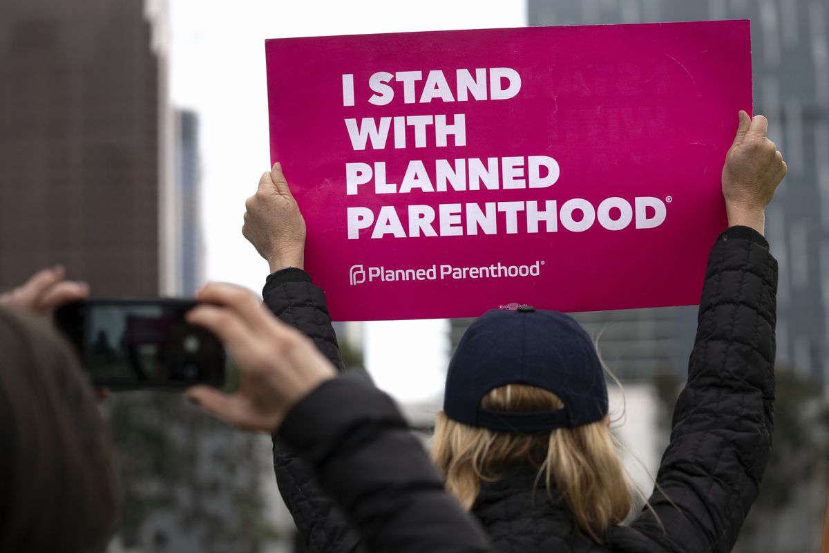 An activist holds a sign reading, “I stand with Planned Parenthood.”