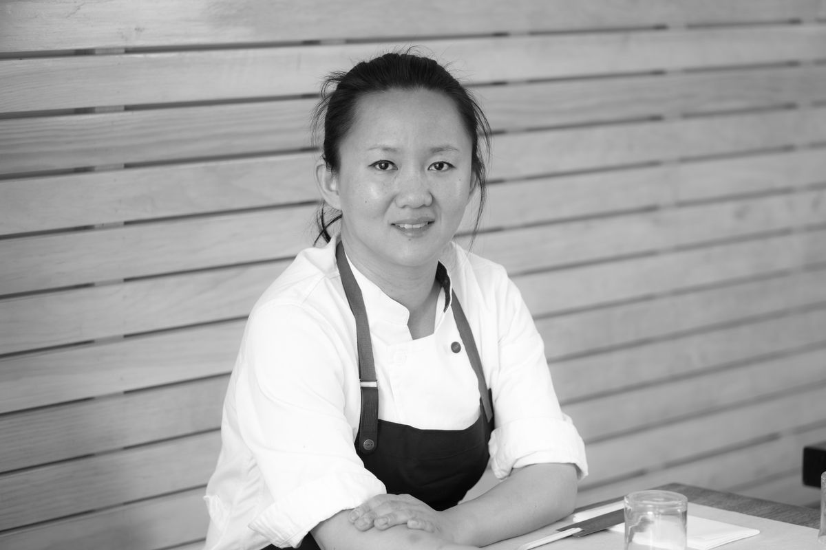 Simone Tong sits at a table with her hair pulled back and an apron on